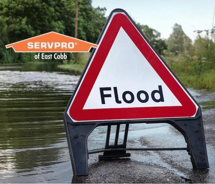 a street completely submerged in water and a flood warning sign in roadway
